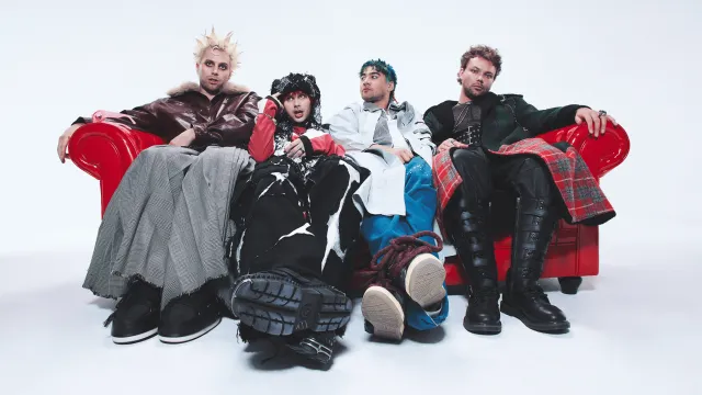 5 Seconds Of Summer, Luke, Michael, Calum e Ashton sentados num sofá vermelho.